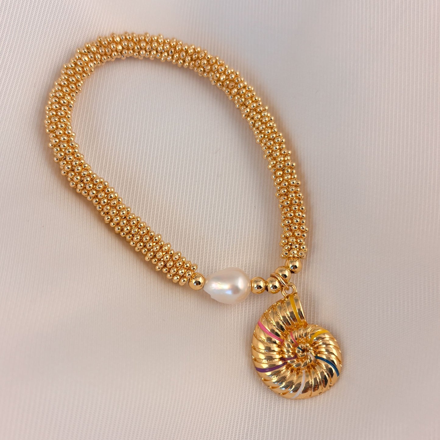 Pulsera rueditas perla y dije Corazón rojo o caracol chapa de oro